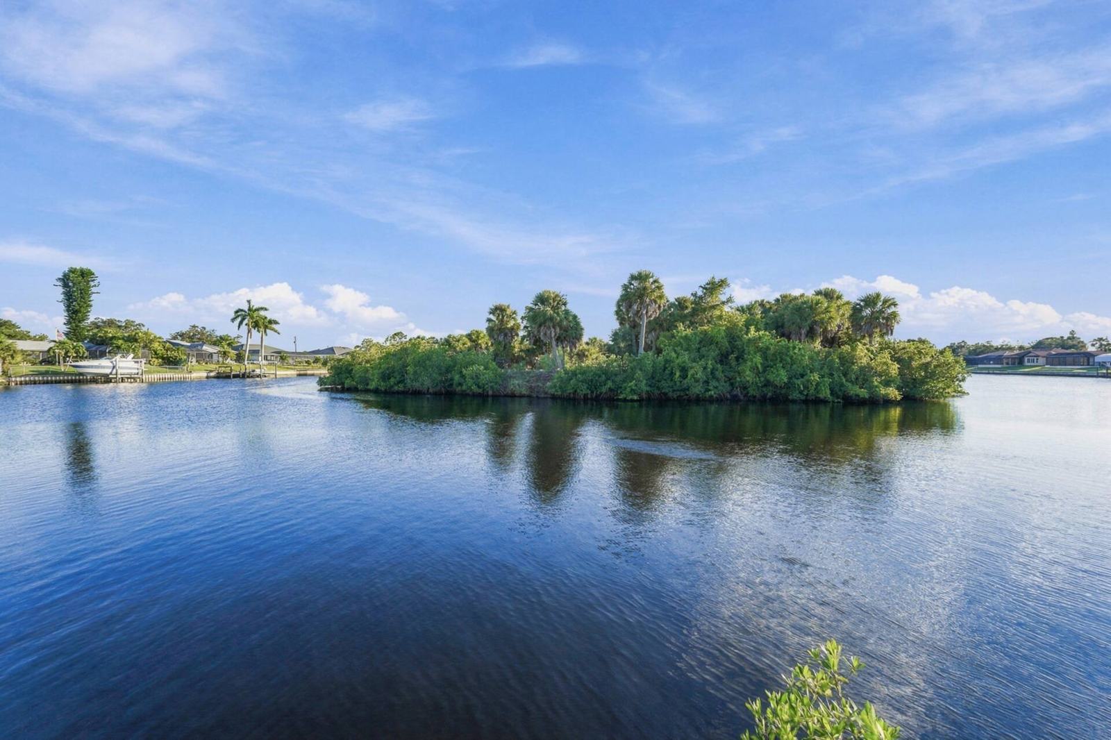 Calm canal water and a mangrove island under blue sky