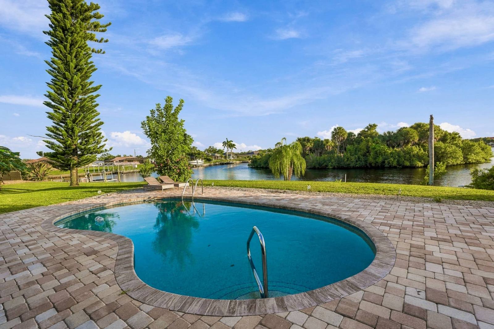 Private pool on a paver deck overlooking a wide canal