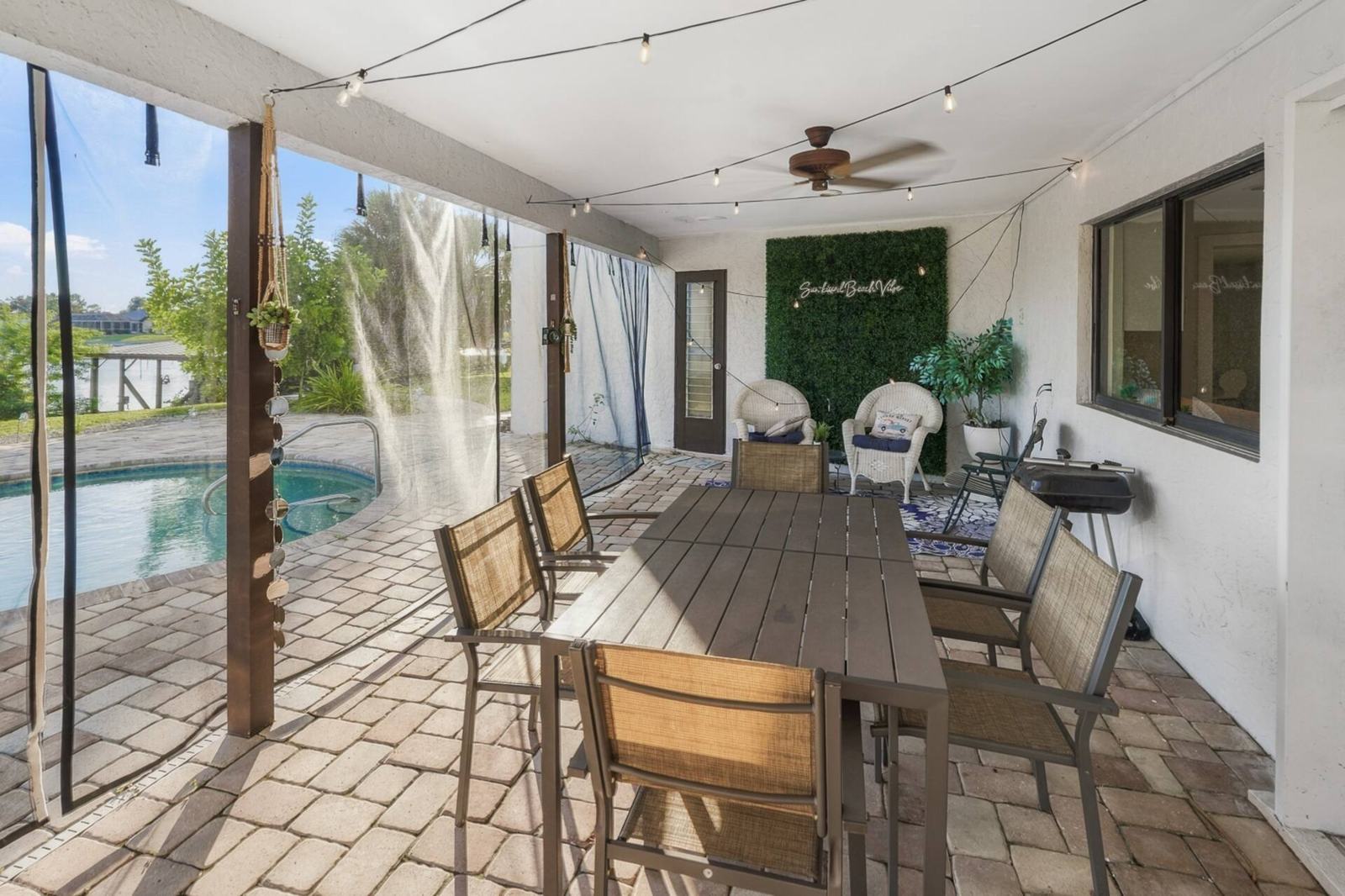 Covered lanai with outdoor dining table next to the pool
