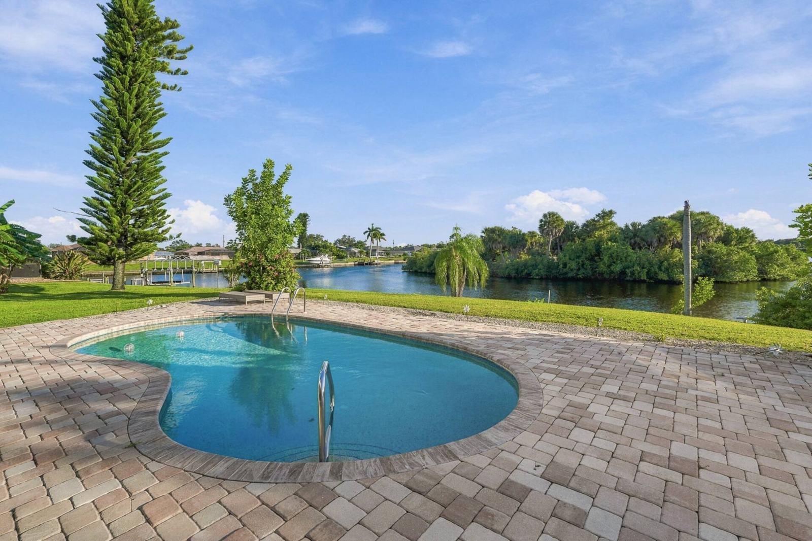 Kidney-shaped pool with the canal and trees beyond